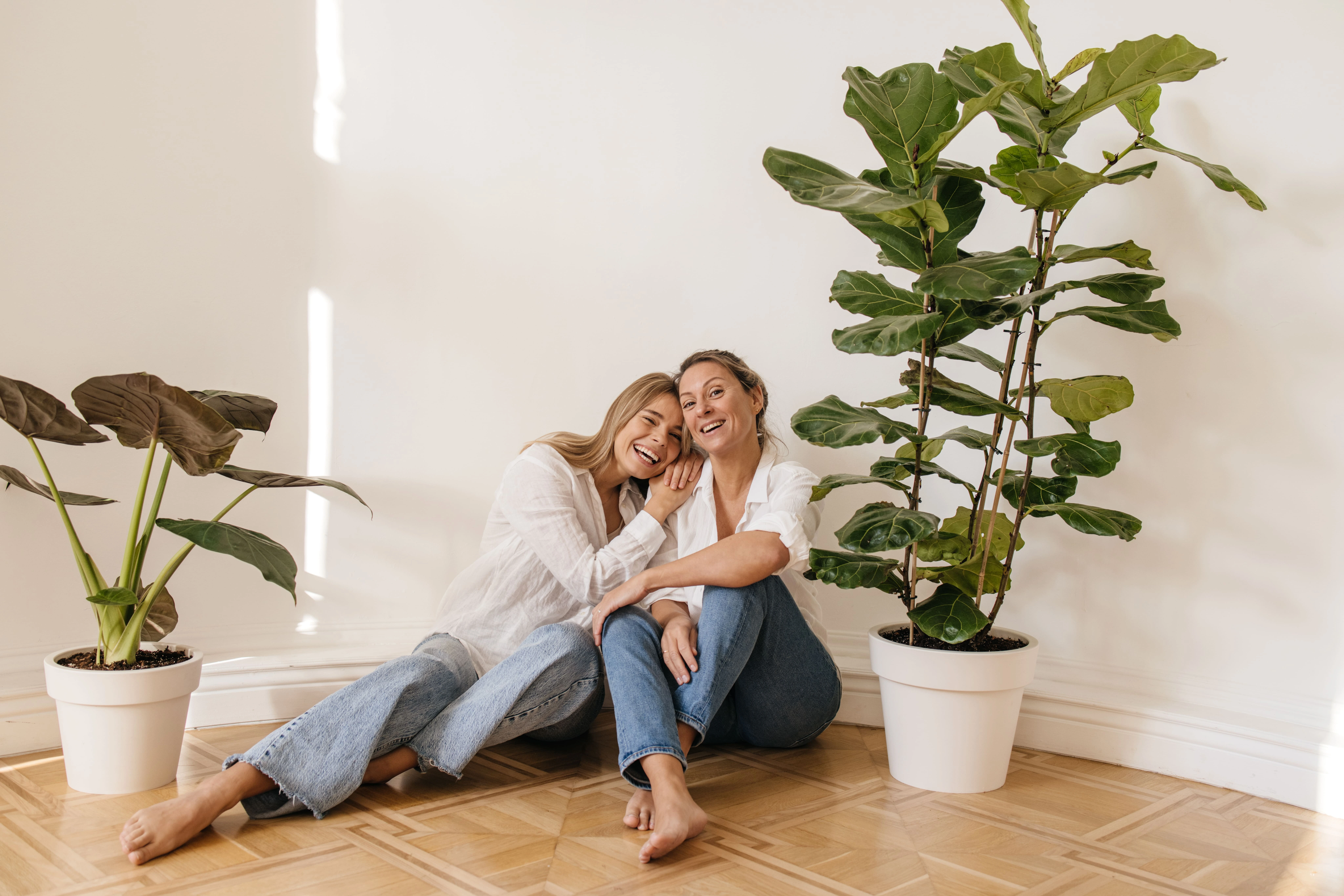 positive-caucasian-blonde-girls-different-ages-sit-floor-empty-room-against-white-wall-concept-enjoying-weekend-vacation